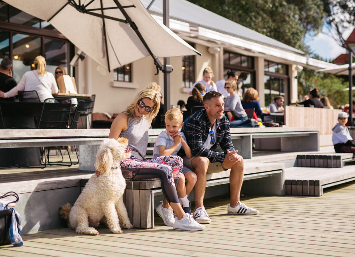 Happy family at Hobsonville Point enjoying sun in front of a café